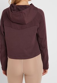 Bordeauxfarbene, verkürzte Kapuzenjacke mit geripptem Textur an den Schultern und der Kapuze. Sie besticht durch ein weiches Material und einen lässigen Schnitt.
