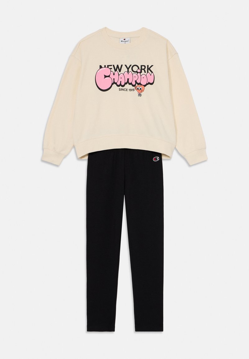 Cream sweatshirt with "New York Champion" graphic, paired with black elastic waistband pants featuring a small logo on the side.