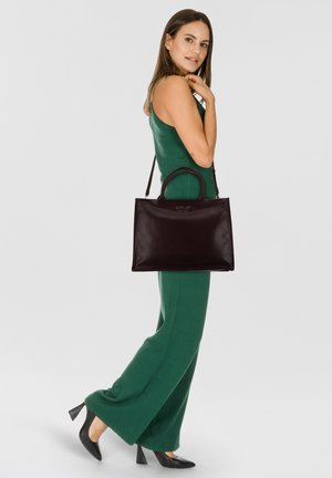 Bolso de cuero negro con dos asas redondeadas y una base plana. El bolso presenta un sutil detalle del logo en la parte frontal y una textura suave.