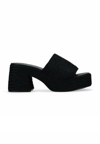 Mules negros de cuña con un upper de tejido texturizado y trenzado y un tacón grueso y estriado. Cuenta con una tira ancha en el empeine para mayor soporte.