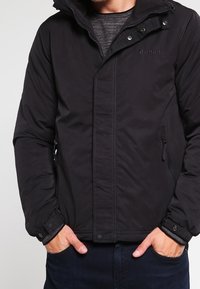 Czarna pikowana kurtka z zamkiem błyskawicznym, zatrzaskami oraz bocznymi kieszeniami. Posiada kaptur oraz haftowane logo "Bench." na piersi.