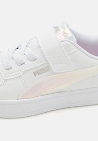 Witte sneaker met synthetisch bovenwerk, klittenbandsluiting en textuur rubberen zool. Heeft een metallic zilveren logo en een iriserende zijstreep detail.