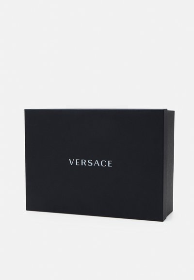 Černá kartonová krabice s plochým designem. Na přední straně je vytištěn bílý nápis "VERSACE" uprostřed. Minimalistická s ostrými rohy.