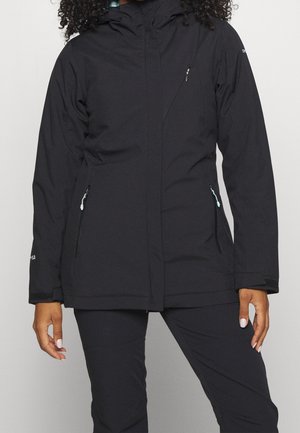 Schwarze langärmlige Kapuzenjacke mit Reißverschlusstaschen, getragen von einer Person mit lockigem Haar, gezeigt von den Schultern bis zur Mitte des Oberschenkels.