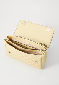 Borsa a tracolla gialla trapuntata con chiusura a scatto magnetico, caratterizzata da due scomparti foderati con tessuto con marchio e dettagli hardware color oro.