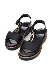 Černé kožené sandály se zlatým kovovým detailem, širokými popruhy, polstrovanou vložkou a silnou, texturovanou podrážkou.