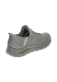 Scarpa sportiva grigia con tomaia sintetica testurizzata, suola ammortizzata e design con lacci. Caratterizzata da un tallone trapuntato con dettagli di branding.