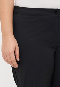 Black trousers featuring a smooth, lightweight fabric with a structured waistband and a single button closure detail.