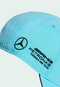 Lichtblauwe baseballcap van stof, met een zwart Mercedes-logo en de tekst "PETRONAS FORMULA ONE TEAM" op de zijkant gedrukt.