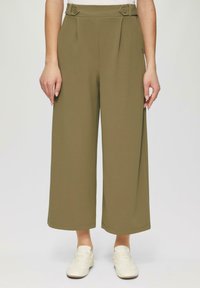 Olijfgroene wijde broek met plooien bij de taille, voorzien van knoopaccenten en een gladde stoftextuur, gecombineerd met witte sneakers.