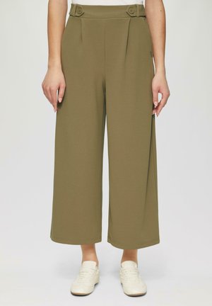 Olijfgroene wijde broek met plooien bij de taille, voorzien van knoopaccenten en een gladde stoftextuur, gecombineerd met witte sneakers.