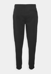 Zwarte sweatpants met een taps toelopende pasvorm, gemaakt van zachte stof. Voorzien van een elastische tailleband en een enkele achterzak.