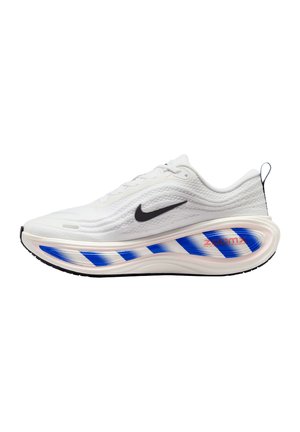 Weißer Nike Laufschuh mit schwarzem Swoosh-Logo, dicker Sohle mit blau-weiß gestreiftem Muster und rotem "ZoomX" Text auf der Zwischensohle.