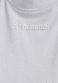 Hvid atletisk top lavet af tekstureret stof, med et hævet "hummel" logo i hvid. Designet inkluderer en rund halsudskæring og syningsdetaljer.