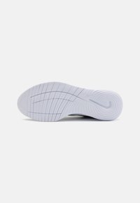 Semelle de chaussure avec une surface en caoutchouc blanc, présentant un motif de grip texturé et des rainures horizontales pour l'adhérence. Forme incurvée au niveau du talon.