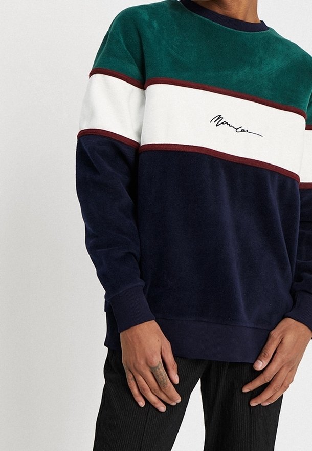Sudadera de bloques de color que presenta paneles en verde, blanco, burdeos y azul marino. Confeccionada con tela suave, cuello redondo y detalle de logo bordado.