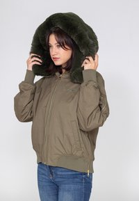 Olijfgroene bomberjack met een faux fur capuchon, ritssluiting en geribde manchetten. Beschikt over zijzakken en een relaxed fit ontwerp.