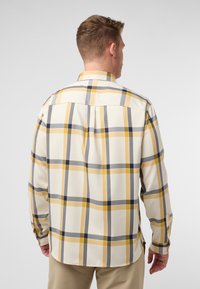 Heren overhemd met lange mouwen in crème, met een groot geel, grijs en marineblauw ruitpatroon. Het heeft een standaard kraag en knoopmanschetten.