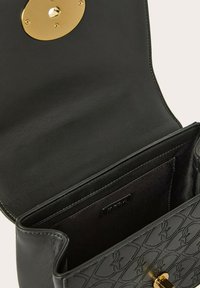 Borsa a mano in pelle nera con una texture liscia, chiusura ovale in oro e motivo impresso che presenta piccoli disegni all'esterno e un interno ben organizzato.