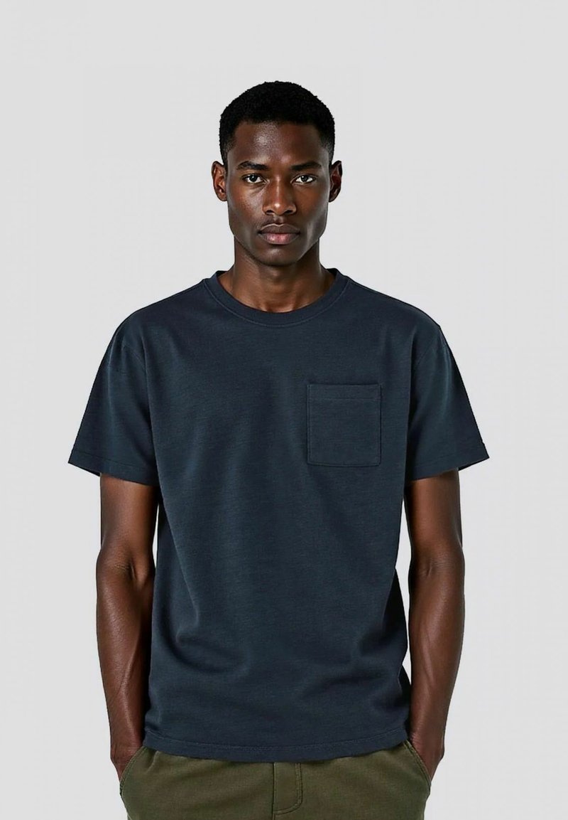 T-shirt in cotone blu navy con scollatura rotonda, maniche corte e taschino frontale. Tessuto liscio, vestibilità comoda, design semplice.