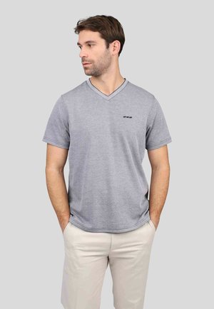 T-shirt gris à col en V en tissu doux avec une coupe décontractée. Doté de manches courtes et d'un détail de logo discret sur la poitrine. Associé à un pantalon clair.