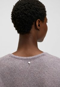 Liliowa sweter wykonany na drutach o miękkiej teksturze, z okrągłym dekoltem i małym metalowym guzikiem z tyłu.