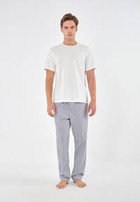 Tricou alb cu maneci scurte combinat cu pantaloni de pijama în dungi albastre și albe, având un tiv elastic și un design cu picioare drepte.