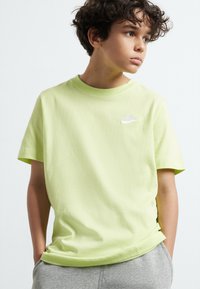 Rövid ujjú, világoszöld pamut póló, fehér Nike logóval a mellrészen, puha tapintású és normál szabású.