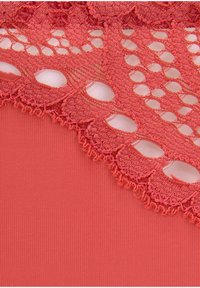 Korallfärgad tyg med intrikat spetsdekoration med öppna mönster och texturerade kanter. Den släta bakgrunden kontrasterar med spetssyn.