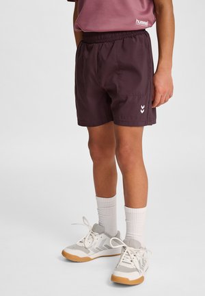Paarse sportshorts met een elastische tailleband, voorzien van het witte Hummel-logo en chevronaccenten, gecombineerd met grijze en witte sneakers.