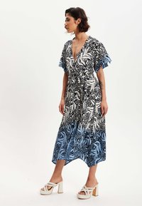 Floral print dress in black, white, and blue. Short flutter sleeves, V-neck, cinched waist, and flowing hem with a slight high-low cut.