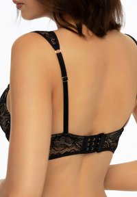 Black lace bralette featuring a scalloped edge, adjustable straps, and a three-hook closure at the back. Soft, patterned fabric.