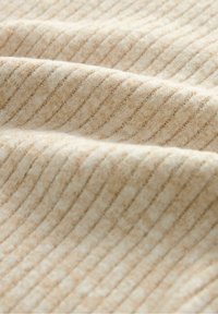 Beżowa tkanina w paski o miękkiej, teksturowanej powierzchni. Cienkie, naprzemiennie jasne i ciemne paski tworzą subtelny wzór.