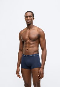 Marineblaue Baumwoll-Boxershorts mit einem weichen, elastischen Bund, der das weiße "GANT"-Logo zeigt. Einfaches Design mit einer anliegenden Form.