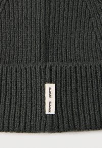 Gorro de punto acanalado gris oscuro con una textura suave y una pequeña etiqueta blanca con el nombre de la marca "Samsøe Samsøe" cosida en un lateral.