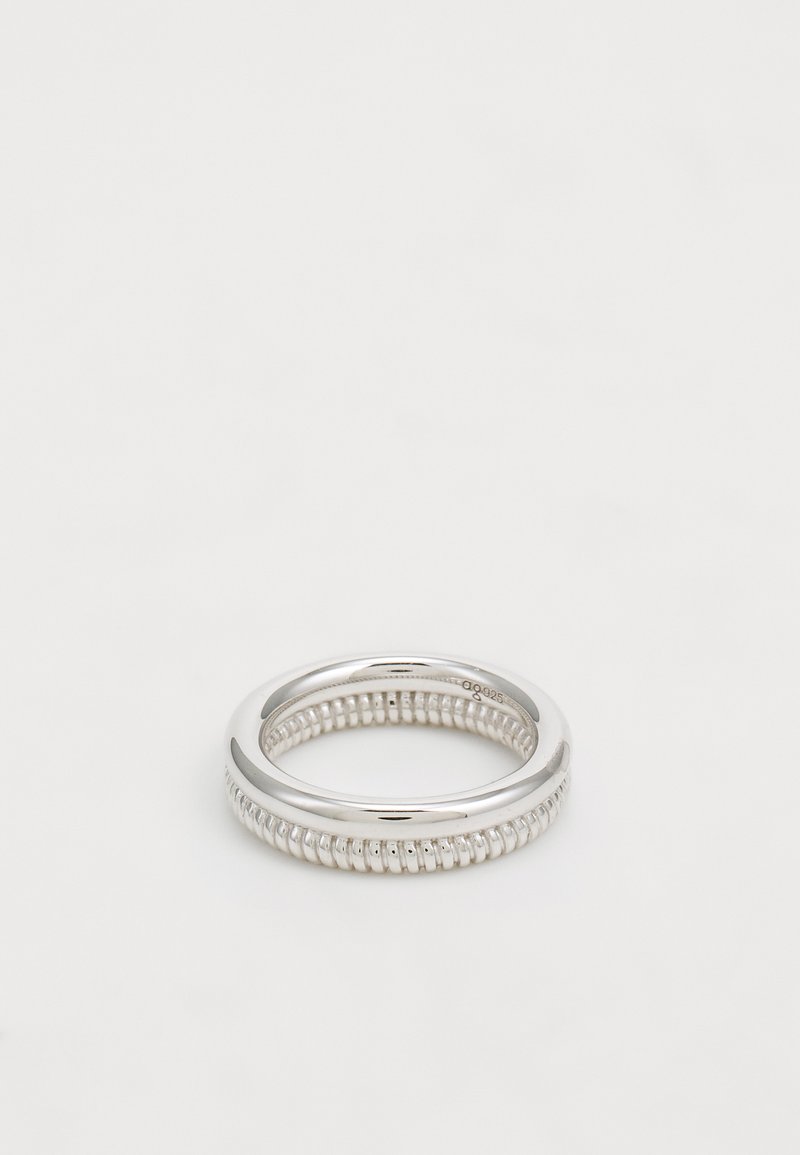 Sudraba gredzens ar gludu, pulētu ārējo joslu un teksturētu iekšējo joslu ar mazām iegriezumiem. Vienkāršs, apaļš dizains.