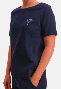 Granatowy bawełniany T-shirt z krótkim rękawem, okrągłym dekoltem i haftowanym logo na piersi. Miękka tekstura i luźny krój.