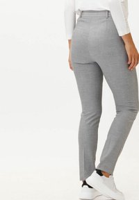 Gray tailored pants made of textured fabric, featuring a slim fit and side slits at the hem, paired with white athletic shoes.