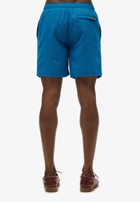 Blauwe shorts van lichtgewicht stof met een elastische tailleband, zijzakken en een achterzak met een opvallende oranje accent.