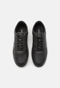 Baskets en cuir noir avec des détails perforés, lacets plats et un logo subtil. Comprend un col rembourré et une semelle en caoutchouc texturée.