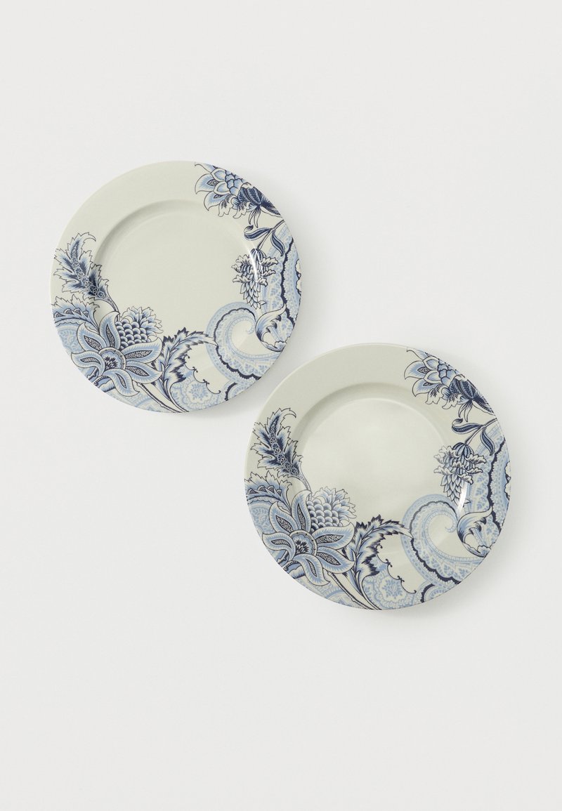 Deux assiettes en céramique blanche ornées de motifs floraux et paisley bleus le long des bords sur un fond blanc.