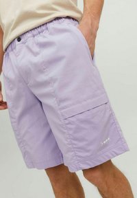 Light purple shorts made of lightweight fabric with an elastic waistband and side cargo pocket. Features subtle branding near the hem.