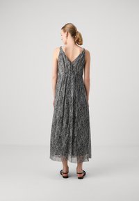 Robe maxi à motifs noir et blanc avec un dos en V, des bretelles ajustables et une silhouette fluide. Tissu léger et texturé.
