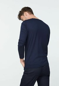 Marineblaues Longsleeve-T-Shirt aus weichem Material, mit rundem Halsausschnitt und figurbetontem Schnitt, von hinten betrachtet. Keine auffälligen Muster.