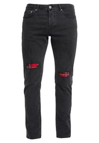 Jeans de mezclilla negros con desgarros que revelan una tela de cuadros rojos debajo. Diseño de corte ajustado, estilo de cinco bolsillos y detalles de desvanecimiento sutiles.