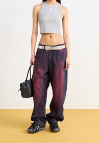 Grå kort tanktop, oversized mörkviolett jeans med blekning, spikad silverbälte, svart handväska och svarta sneakers. Enkla designinslag.