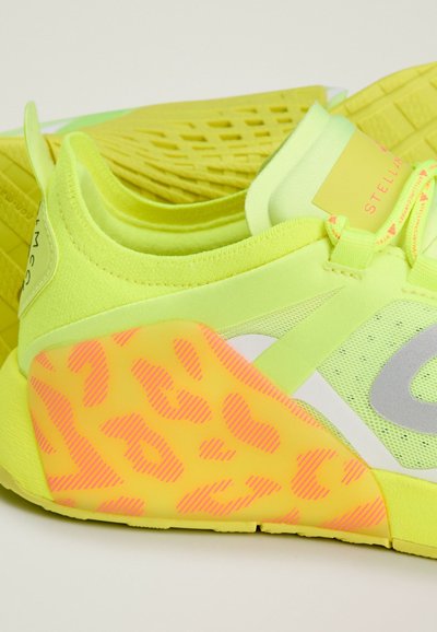 Neon yellow athletic shoe with mesh and textured rubber accents. Features a leopard print design in pink and sleek, streamlined shape.