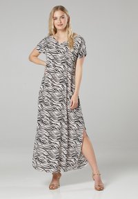 Maxikleid mit Wellenmuster in Schwarz auf hellem Hintergrund, kurzen Ärmeln, seitlichem Schlitz und glattem Stoff.