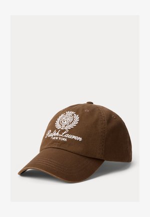 Brūna kokvilnas beisbola cepure ar izliekumu, ar baltu izšūtu logotipu un uzrakstu: "Ralph Lauren New York." Klasisks dizains.