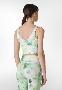 Sujeción deportiva de estampado floral verde y leggings a juego, hecho de una tela elástica con una textura suave, con tirantes anchos y cintura alta.